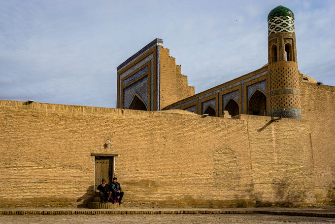 Hai người đàn ông lớn tuổi đang ngồi nghỉ dưới chân một bức tường 600 năm tuổi ở Khiva. Thành phố này là điểm đầu tiên ở Uzbekistan được đưa vào di sản UNESCO.